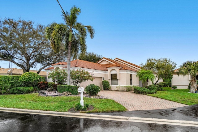 mediterranean / spanish home featuring a garage and a front lawn