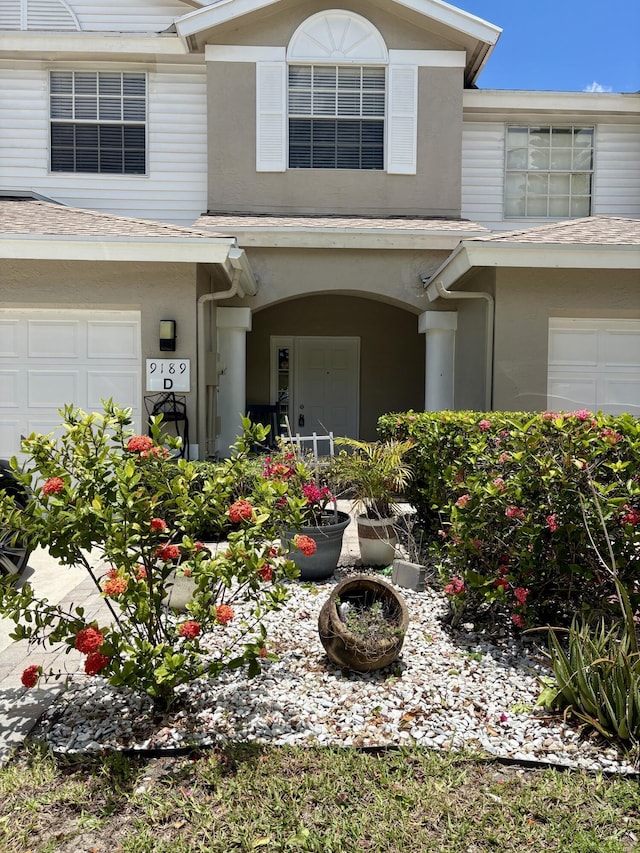 9189 Boca Gardens Cir Unit D, Boca Raton, FL 33496 - view of front of house with an attached garage, a shingled roof, and stucco siding