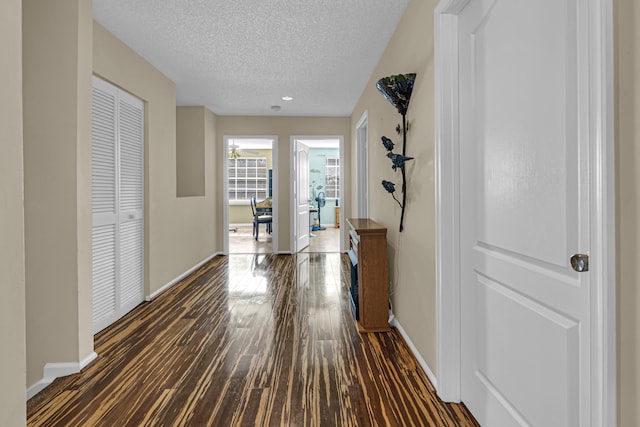 corridor with dark hardwood / wood-style flooring and a textured ceiling