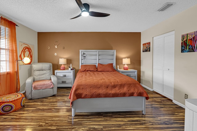 bedroom featuring dark wood-type flooring, ceiling fan, a closet, and a textured ceiling