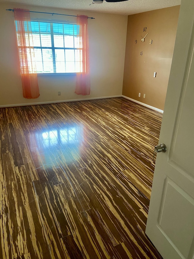 spare room with dark wood-type flooring and a textured ceiling