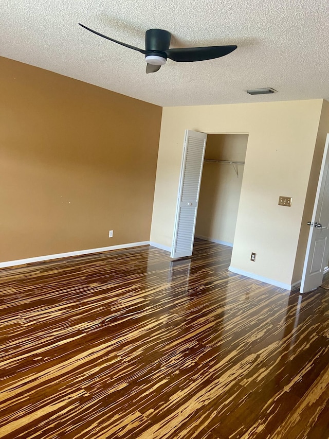 unfurnished bedroom with dark hardwood / wood-style flooring, a textured ceiling, a closet, and ceiling fan