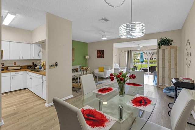 dining area with ceiling fan, sink, a textured ceiling, and light wood-type flooring