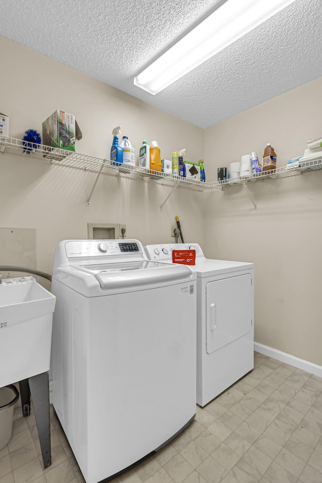 clothes washing area featuring washing machine and dryer and a textured ceiling