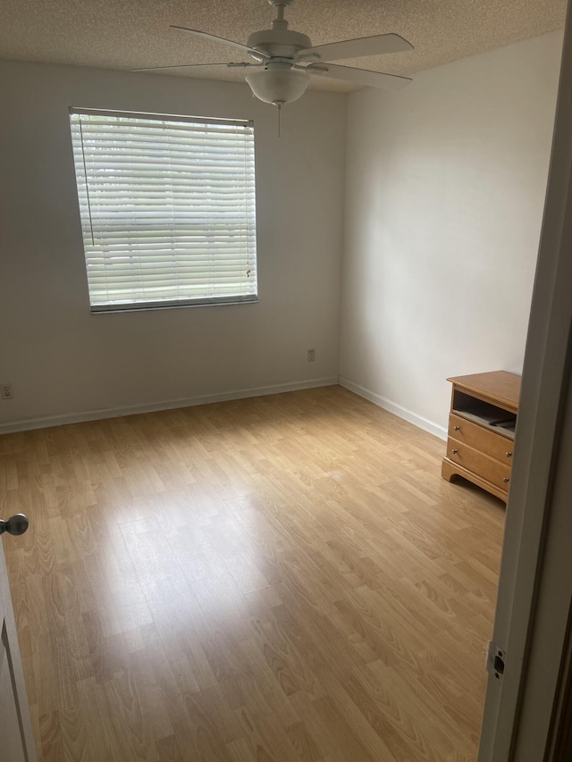 empty room with ceiling fan, a textured ceiling, and light hardwood / wood-style floors