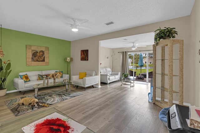 living room featuring hardwood / wood-style floors, a textured ceiling, and ceiling fan