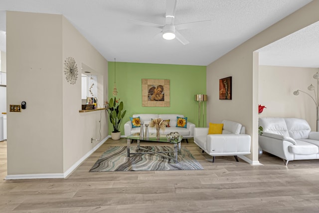 living room with ceiling fan, a textured ceiling, and light hardwood / wood-style floors