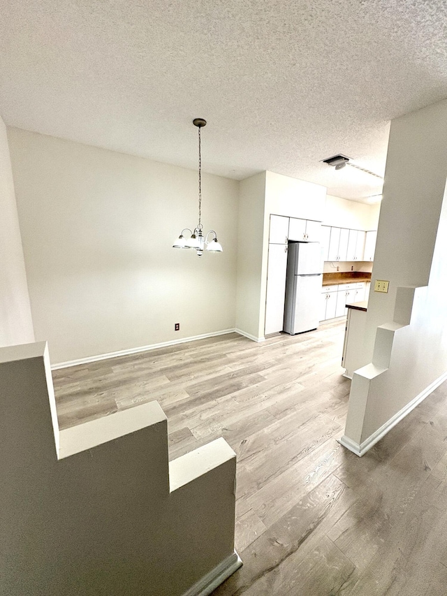 9189 Boca Gardens Cir Unit D, Boca Raton, FL 33496 - unfurnished dining area featuring light wood-type flooring, a chandelier, and a textured ceiling