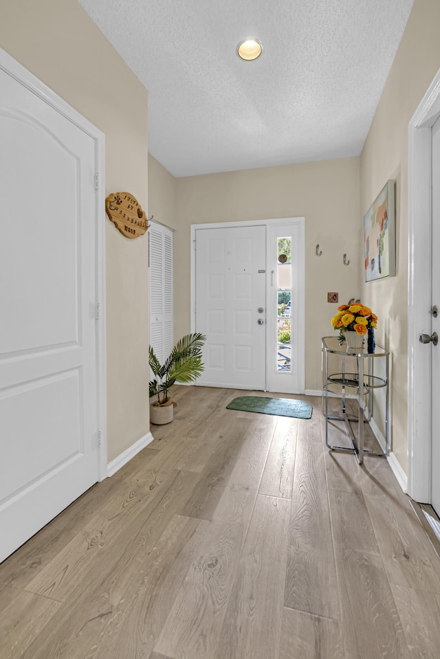 foyer entrance featuring a textured ceiling and light wood-type flooring