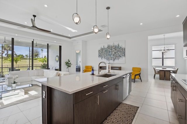 kitchen featuring stainless steel dishwasher, an island with sink, decorative light fixtures, and sink