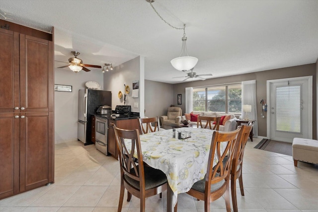 dining space featuring ceiling fan, light tile patterned floors, and a textured ceiling