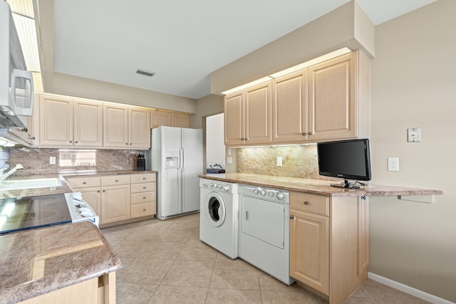 kitchen with tasteful backsplash, independent washer and dryer, light tile patterned floors, and white appliances