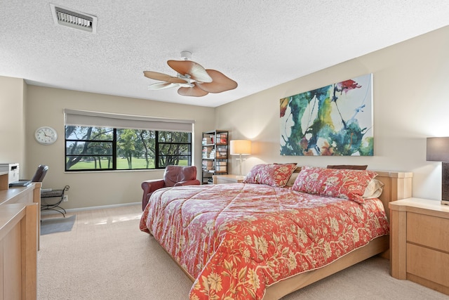 bedroom with ceiling fan, light carpet, and a textured ceiling