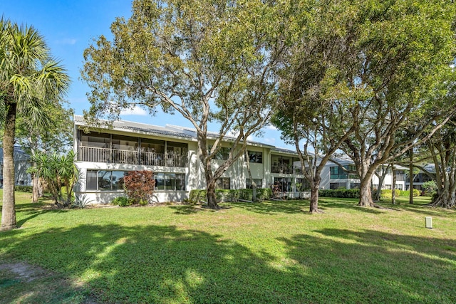 back of property with a yard and a sunroom