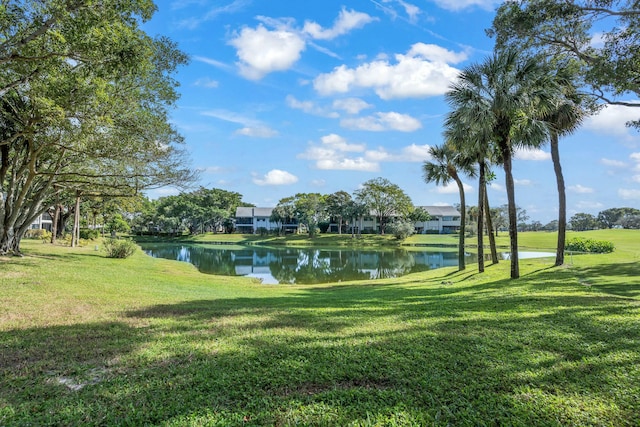 surrounding community with a water view and a lawn