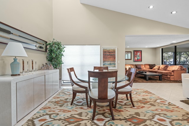 tiled dining room featuring high vaulted ceiling