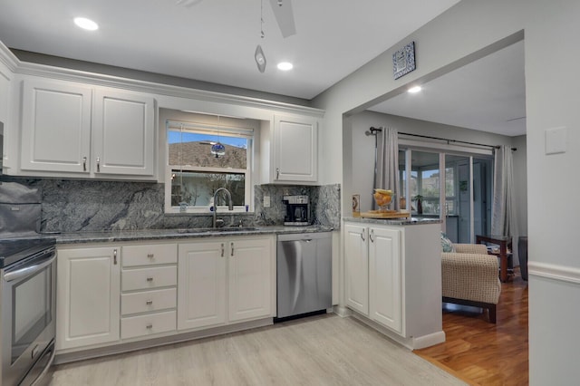 kitchen featuring sink, white cabinetry, dark stone counters, stainless steel appliances, and light hardwood / wood-style floors