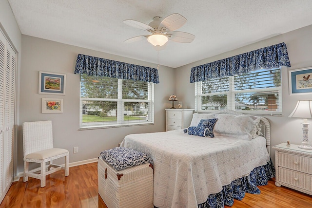 bedroom with ceiling fan, wood-type flooring, a closet, and a textured ceiling