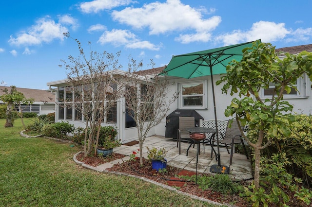 rear view of house with a sunroom, a lawn, and a patio area