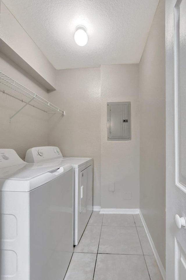 washroom with washing machine and clothes dryer, electric panel, a textured ceiling, and light tile patterned floors