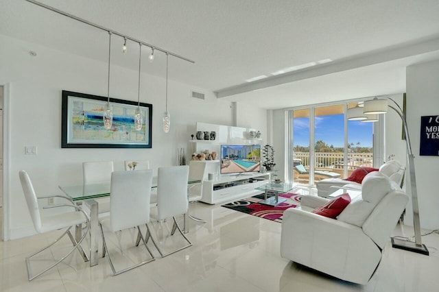 tiled living room featuring expansive windows, rail lighting, and a textured ceiling