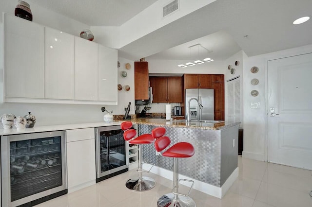 kitchen featuring white cabinetry, stainless steel fridge with ice dispenser, light tile patterned floors, and beverage cooler