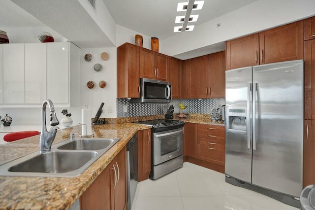 kitchen featuring stainless steel appliances, sink, backsplash, and light stone counters