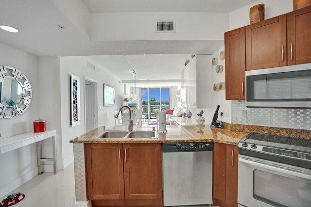 kitchen featuring sink, backsplash, kitchen peninsula, stainless steel appliances, and light stone countertops