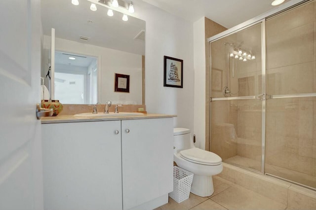 bathroom with tile patterned floors, toilet, a shower with shower door, and vanity