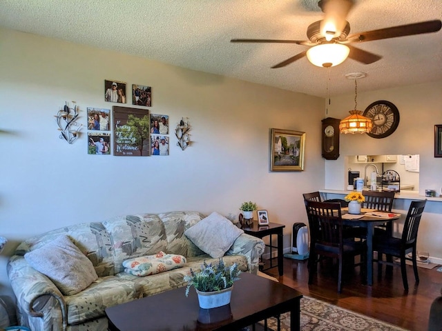 living room featuring a textured ceiling, a ceiling fan, and wood finished floors