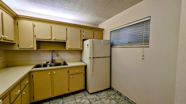 kitchen featuring a textured ceiling, light tile patterned floors, a sink, light countertops, and freestanding refrigerator