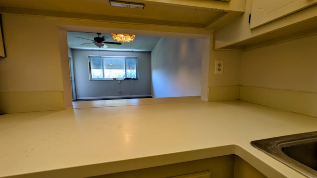 interior space with a ceiling fan, light countertops, a textured ceiling, and white cabinetry