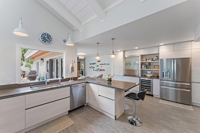 kitchen featuring sink, wine cooler, hanging light fixtures, kitchen peninsula, and stainless steel appliances