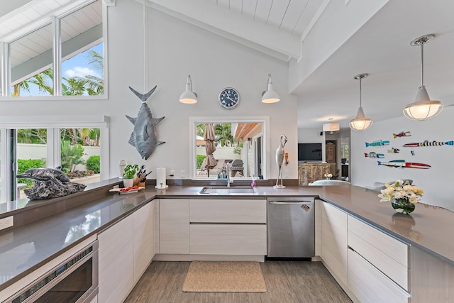 kitchen with dark wood-type flooring, sink, appliances with stainless steel finishes, pendant lighting, and beam ceiling