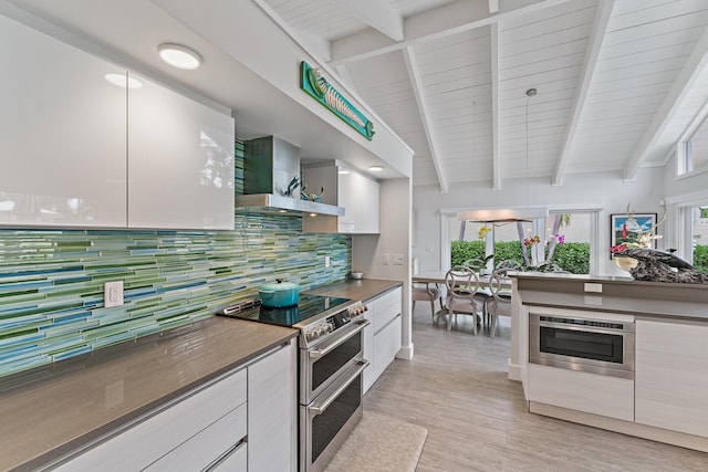 kitchen featuring tasteful backsplash, white cabinetry, stainless steel appliances, and wall chimney exhaust hood