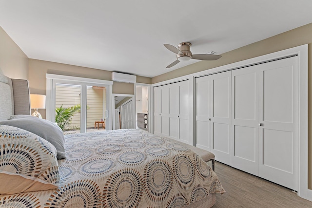 bedroom featuring multiple closets, an AC wall unit, ceiling fan, and light wood-type flooring