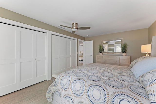 bedroom with two closets, ceiling fan, and light hardwood / wood-style floors