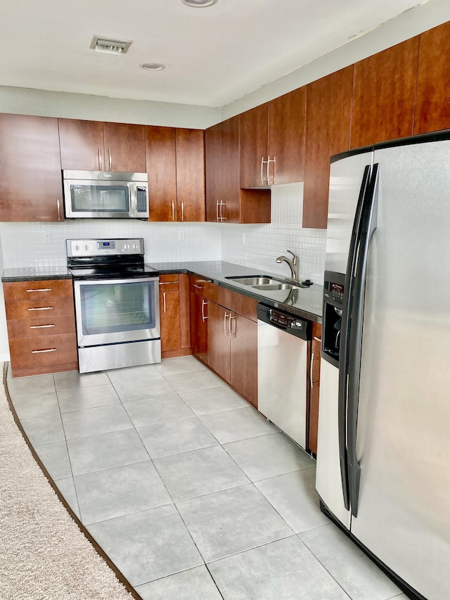 kitchen featuring stainless steel appliances, sink, light tile patterned floors, and decorative backsplash