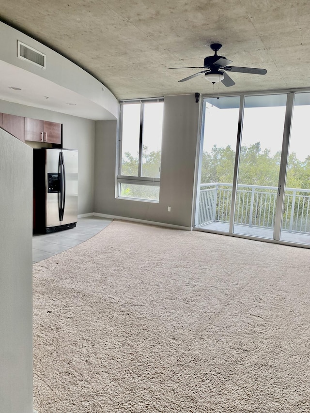 unfurnished living room with expansive windows and ceiling fan