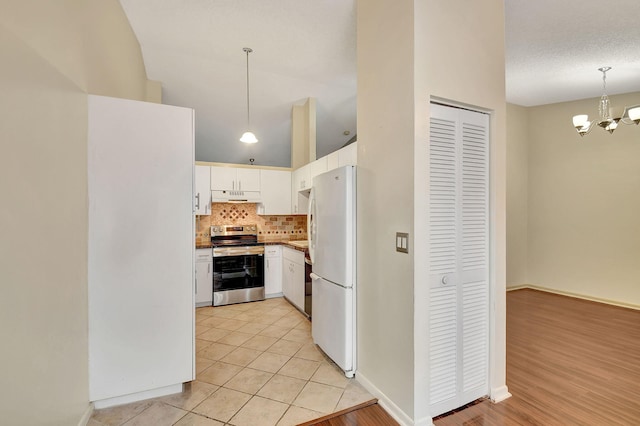 kitchen featuring pendant lighting, white cabinetry, a high ceiling, white fridge, and electric range