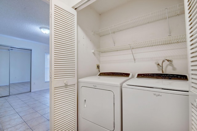 laundry room featuring independent washer and dryer, light tile patterned floors, and a textured ceiling