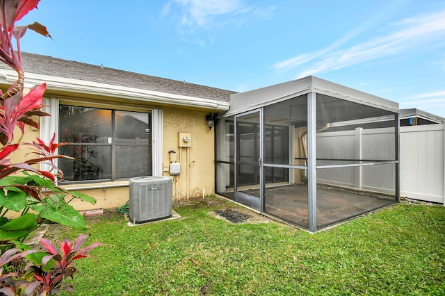 back of property with a sunroom, central AC, and a lawn