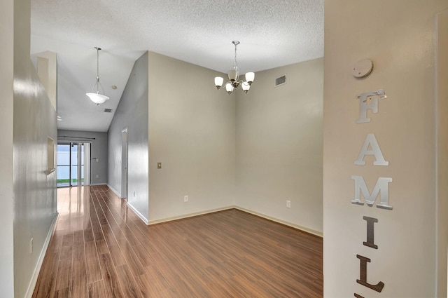 spare room featuring an inviting chandelier, hardwood / wood-style flooring, high vaulted ceiling, and a textured ceiling