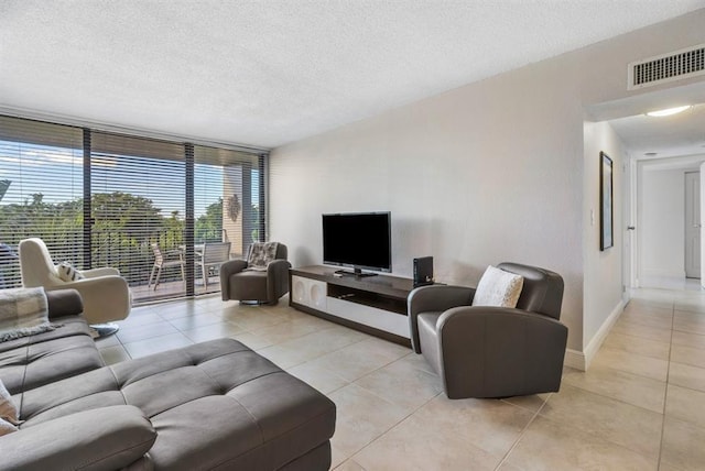 tiled living room featuring a wall of windows and a textured ceiling