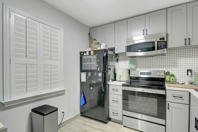 kitchen featuring tasteful backsplash, appliances with stainless steel finishes, gray cabinets, and light hardwood / wood-style floors