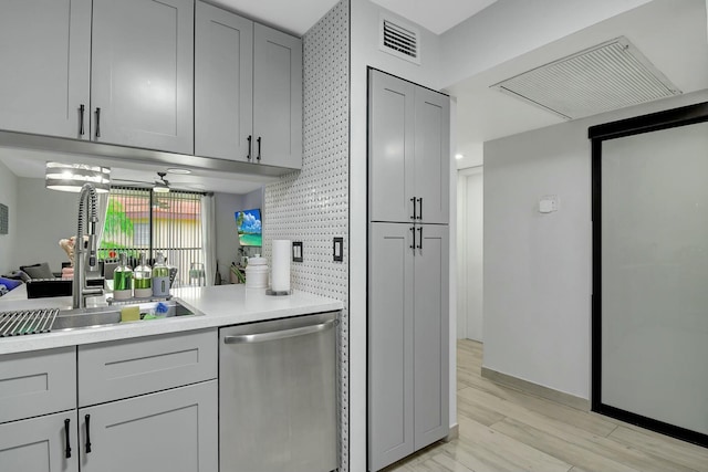 kitchen with sink, gray cabinets, tasteful backsplash, stainless steel dishwasher, and light wood-type flooring