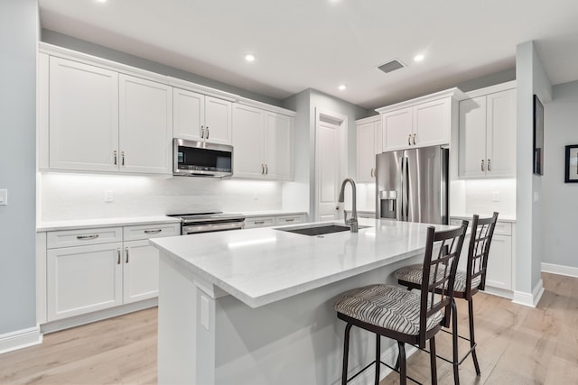 kitchen with stainless steel appliances, sink, a center island with sink, and white cabinets