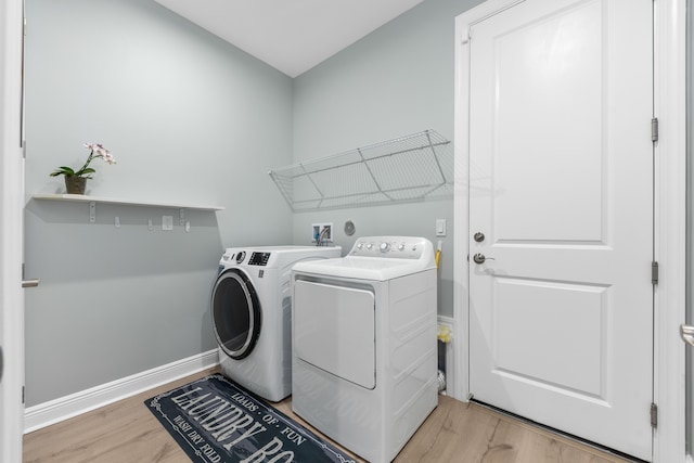 clothes washing area featuring washing machine and dryer and light hardwood / wood-style floors