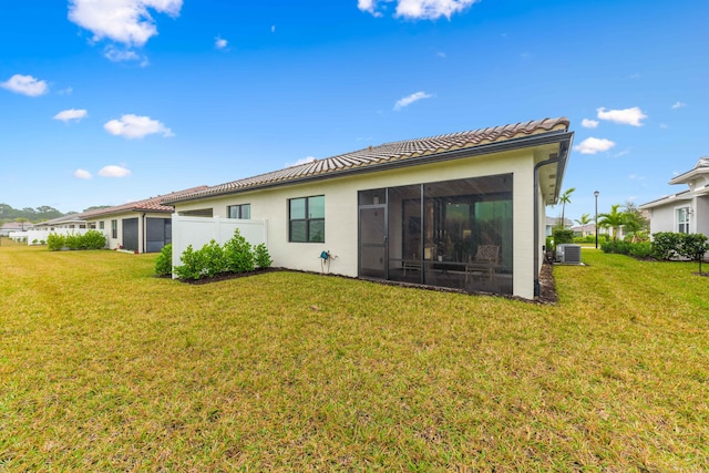 rear view of property with a sunroom, central AC unit, and a lawn