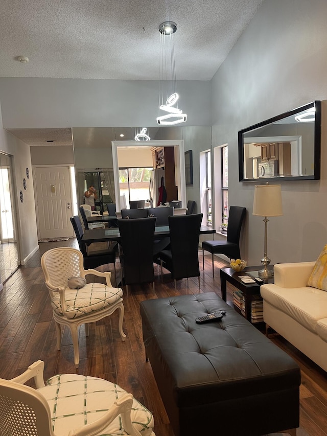 living room featuring a high ceiling, an inviting chandelier, a textured ceiling, and dark hardwood / wood-style flooring